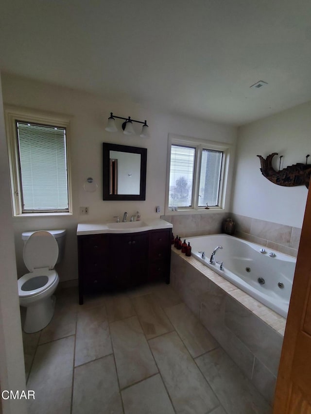 bathroom featuring tile patterned floors, tiled tub, vanity, and toilet