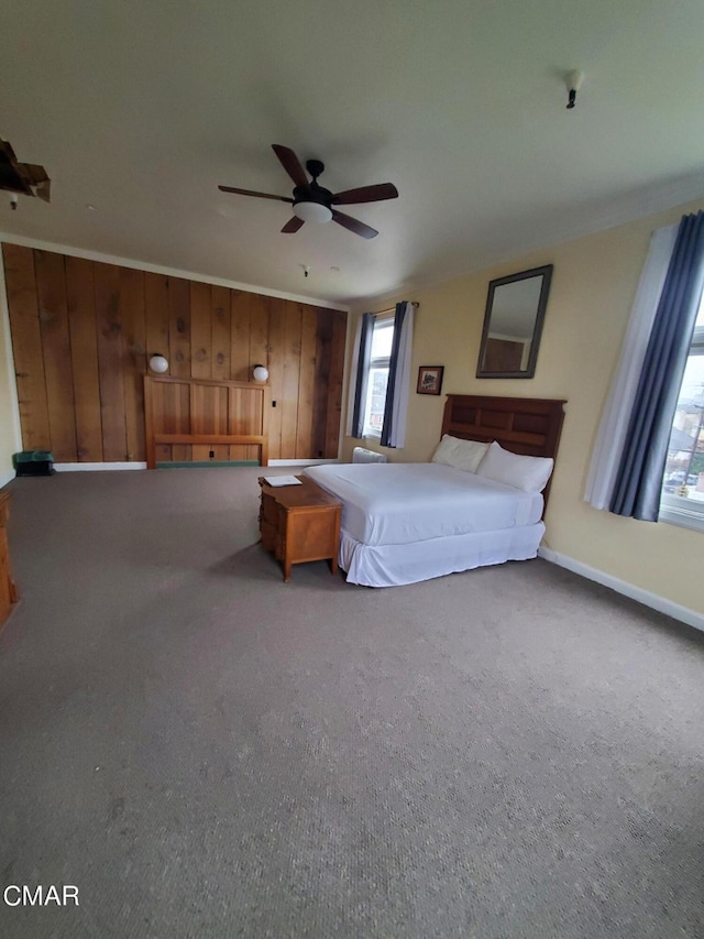 carpeted bedroom featuring ornamental molding, wooden walls, and ceiling fan