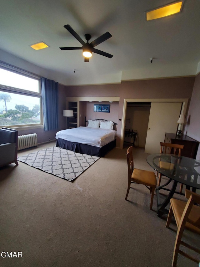 carpeted bedroom featuring ceiling fan, radiator heating unit, and a closet