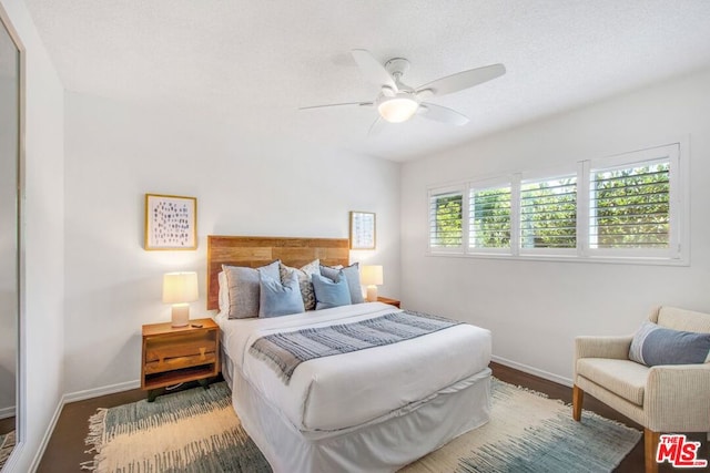 bedroom featuring ceiling fan, wood-type flooring, and a textured ceiling