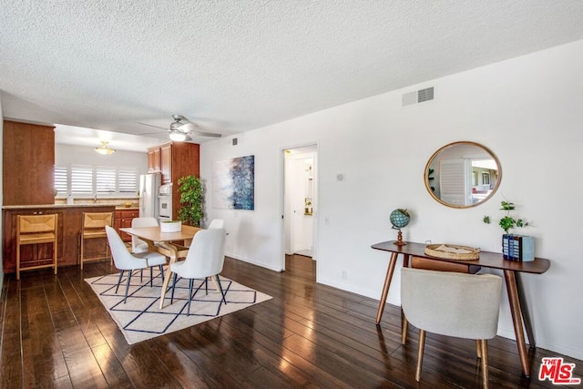 dining space with ceiling fan, dark hardwood / wood-style flooring, and a textured ceiling