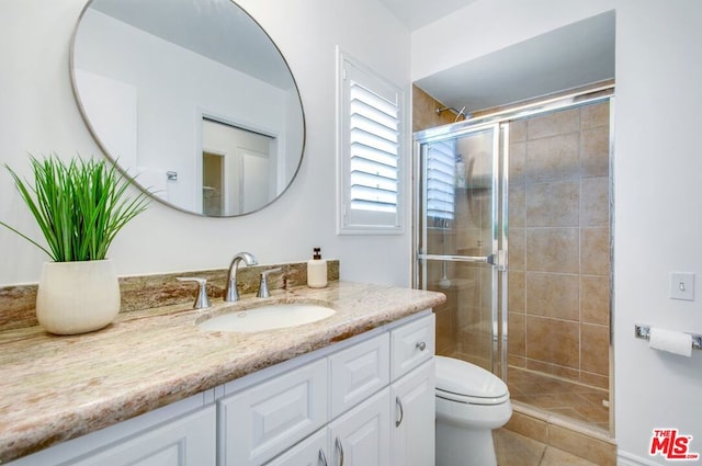 bathroom with tile patterned flooring, vanity, a shower with door, and toilet