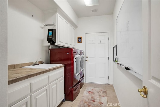 clothes washing area featuring light tile patterned floors, sink, independent washer and dryer, and cabinets