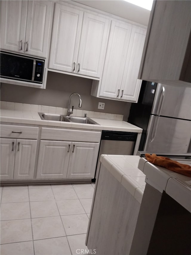 kitchen with light tile patterned floors, stainless steel appliances, white cabinetry, and sink