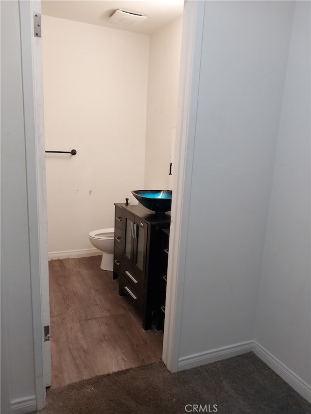 bathroom with hardwood / wood-style floors, vanity, and toilet