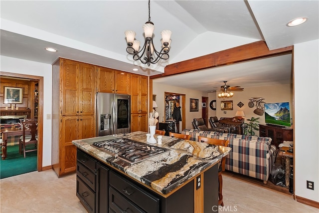 kitchen featuring a center island, ceiling fan with notable chandelier, vaulted ceiling, hanging light fixtures, and appliances with stainless steel finishes