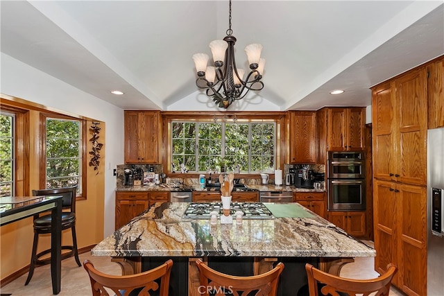 kitchen featuring a kitchen breakfast bar, a kitchen island, a chandelier, and light stone counters