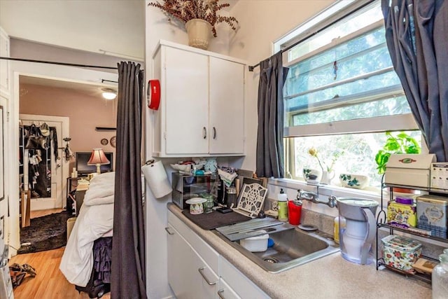 kitchen with white cabinetry, sink, and light hardwood / wood-style floors