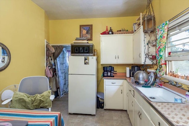 kitchen with white cabinets, white fridge, and sink