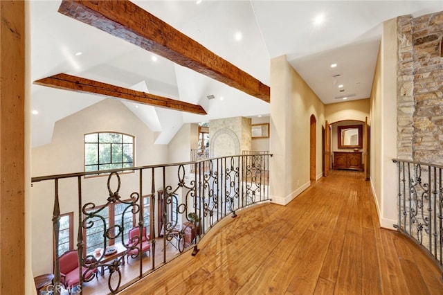 corridor with beam ceiling, light hardwood / wood-style floors, and high vaulted ceiling