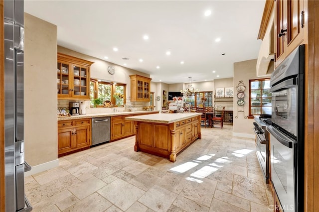 kitchen featuring stainless steel appliances, hanging light fixtures, a notable chandelier, backsplash, and a kitchen island