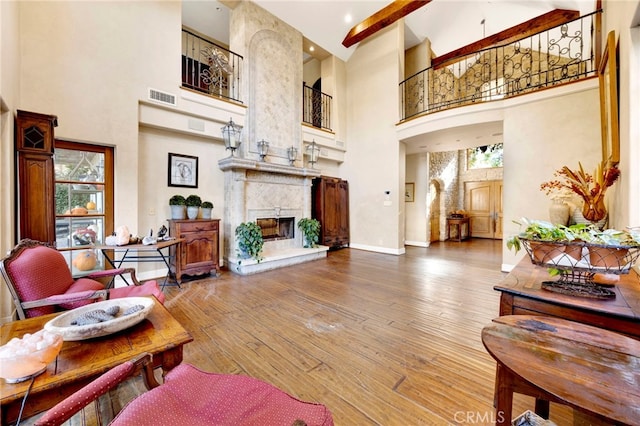 living room with hardwood / wood-style floors, a towering ceiling, and a fireplace