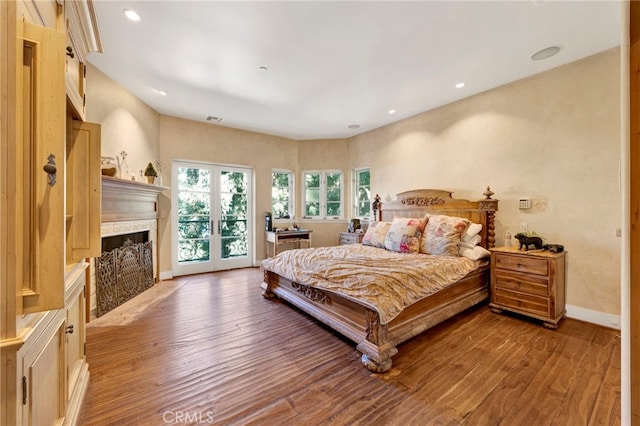 bedroom with access to exterior, a premium fireplace, and light hardwood / wood-style flooring