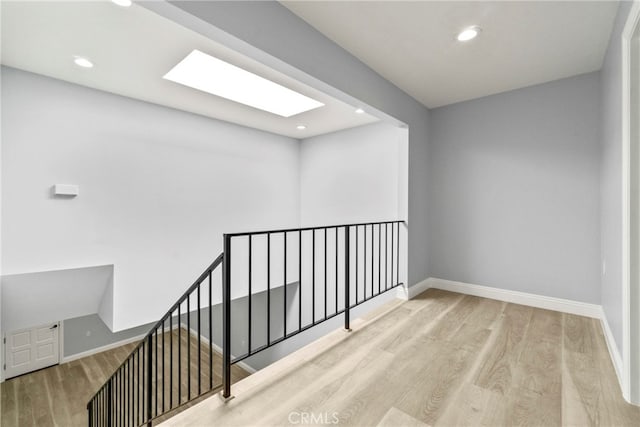 interior space featuring light wood finished floors, baseboards, a skylight, and recessed lighting