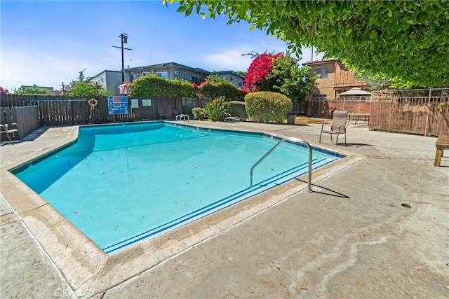 community pool with a patio area and fence