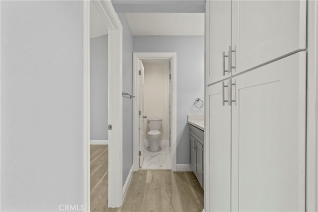 bathroom with vanity, wood finished floors, toilet, and baseboards