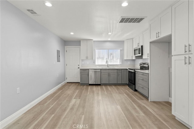 kitchen featuring appliances with stainless steel finishes, light hardwood / wood-style flooring, gray cabinets, and white cabinets