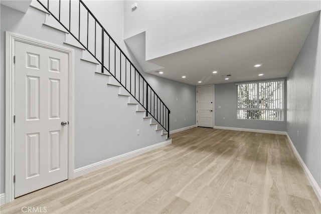 entrance foyer featuring light wood-style flooring, baseboards, and stairs