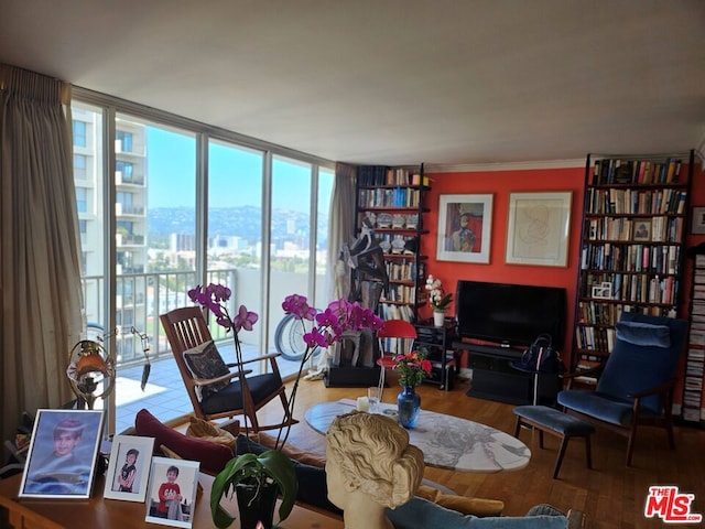 sitting room with floor to ceiling windows, hardwood / wood-style flooring, a healthy amount of sunlight, and crown molding