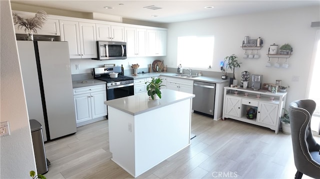 kitchen featuring white cabinets, sink, a kitchen island, light hardwood / wood-style flooring, and stainless steel appliances