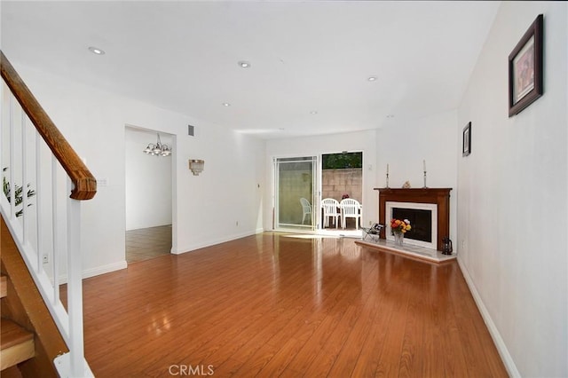 unfurnished living room featuring a chandelier and wood-type flooring