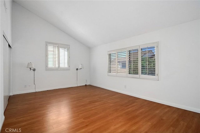 spare room with hardwood / wood-style flooring and lofted ceiling