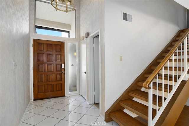 tiled foyer entrance with a towering ceiling and a chandelier