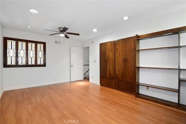 unfurnished bedroom with a textured ceiling, light wood-type flooring, and ceiling fan