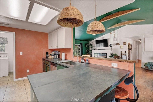 kitchen with washer / dryer, pendant lighting, lofted ceiling with beams, kitchen peninsula, and white cabinets