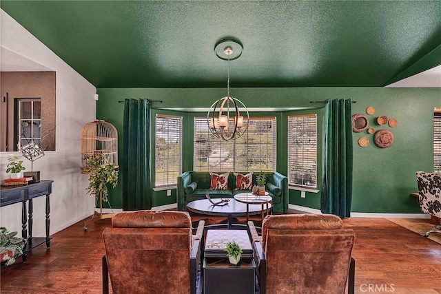 dining area featuring wood-type flooring, lofted ceiling, a notable chandelier, and a textured ceiling