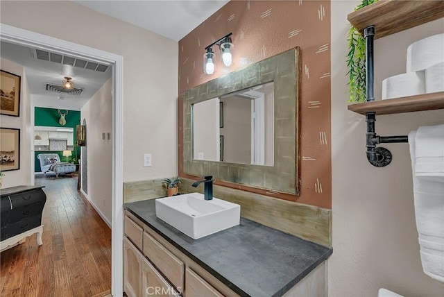 bathroom featuring hardwood / wood-style floors, vanity, and a fireplace