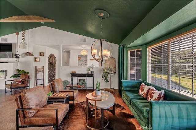 living room featuring wood-type flooring, a notable chandelier, and vaulted ceiling