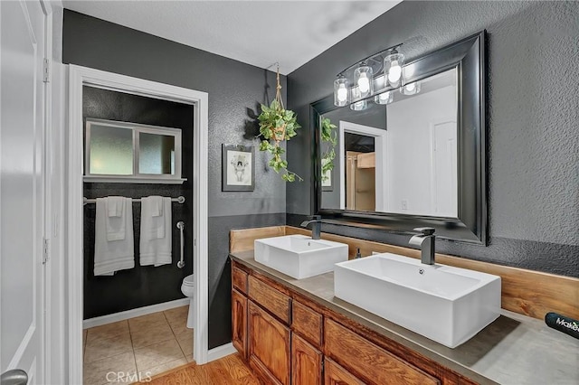 bathroom with toilet, vanity, and tile patterned floors