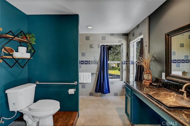 bathroom with tile walls, toilet, vanity, and tile patterned flooring