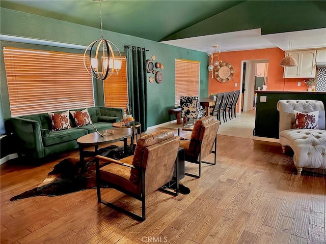 living room featuring lofted ceiling, a chandelier, and light hardwood / wood-style floors