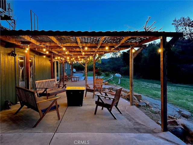 patio terrace at dusk featuring a pergola and a fire pit