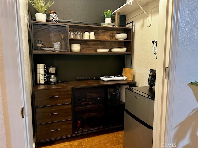 bar with dark brown cabinets and light hardwood / wood-style flooring