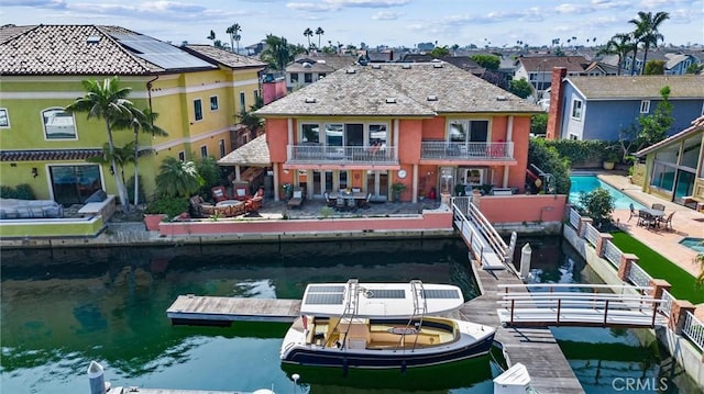 rear view of property featuring a patio area, a balcony, and a water view