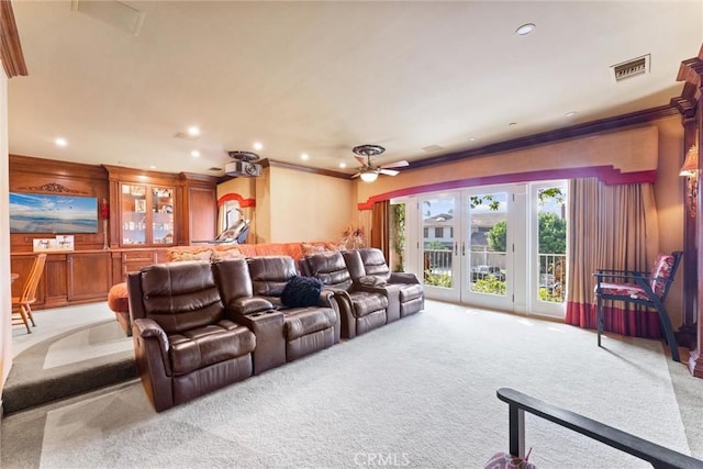 carpeted home theater featuring ceiling fan and ornamental molding