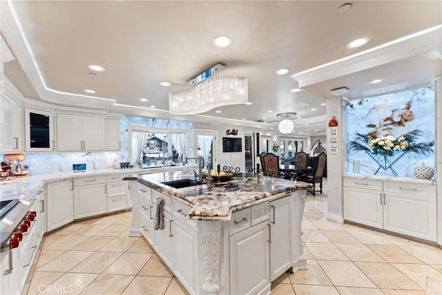 kitchen with light tile patterned flooring, white cabinetry, and an island with sink