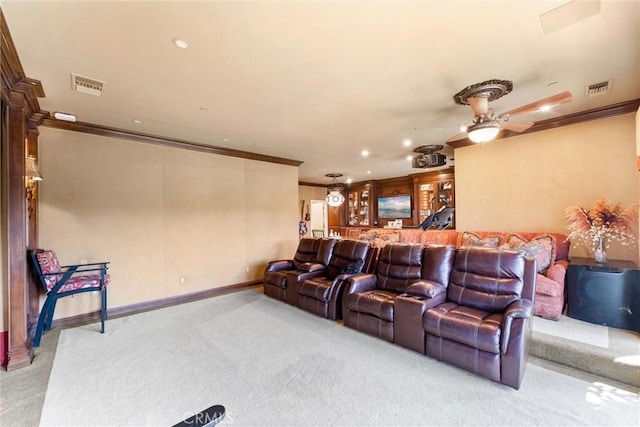 cinema room with ceiling fan, light colored carpet, and ornamental molding