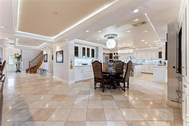 tiled dining room with a raised ceiling and crown molding