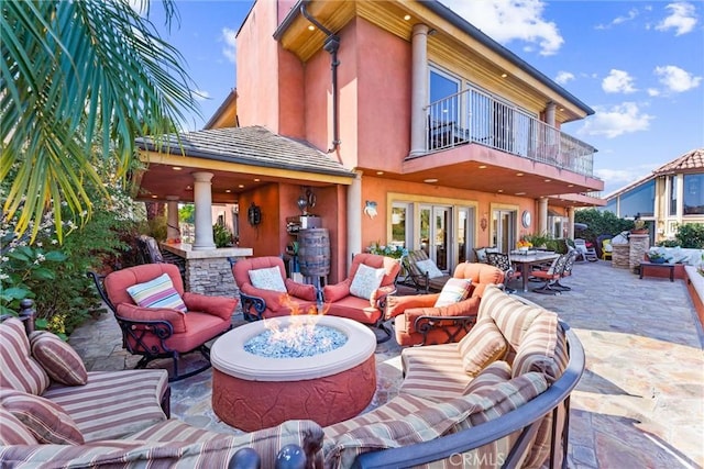 view of patio featuring a balcony and an outdoor living space with a fire pit