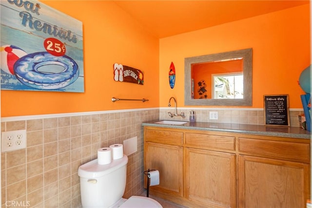 bathroom with vanity, tile walls, and toilet