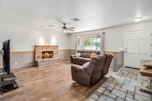 living room featuring ceiling fan, hardwood / wood-style floors, and a brick fireplace