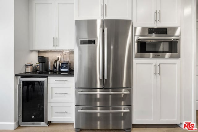 kitchen featuring appliances with stainless steel finishes, backsplash, beverage cooler, and white cabinets