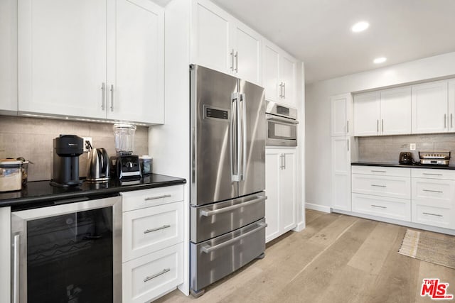 kitchen featuring wine cooler, backsplash, white cabinetry, stainless steel appliances, and light wood-type flooring