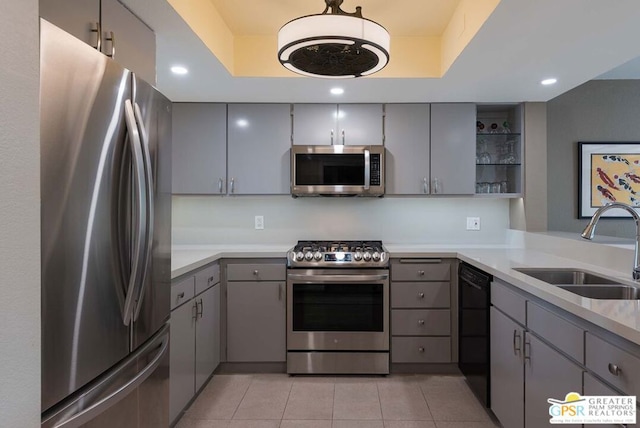 kitchen featuring stainless steel appliances, sink, gray cabinets, a raised ceiling, and light tile patterned flooring