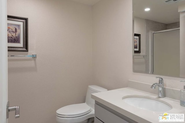 bathroom with toilet, a shower with door, and vanity