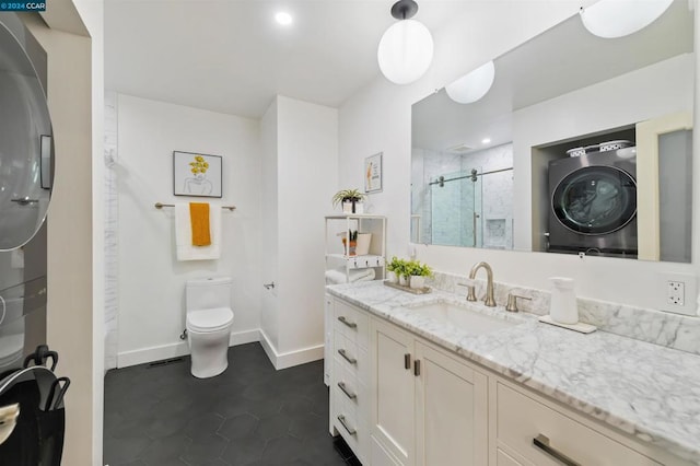 bathroom with toilet, a shower with door, tile patterned floors, vanity, and stacked washer and clothes dryer